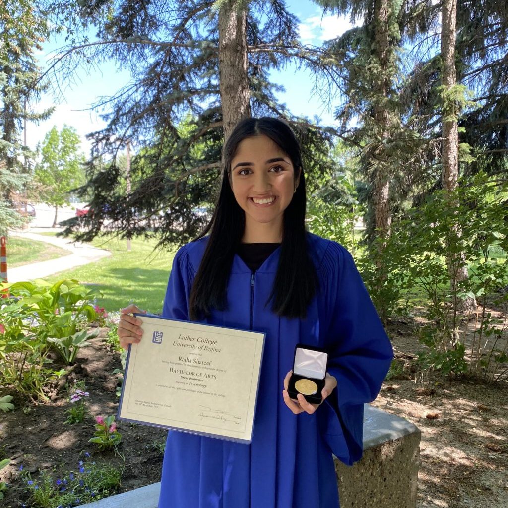 Image of Raiha Shareef outside with her diploma and medal of distinction